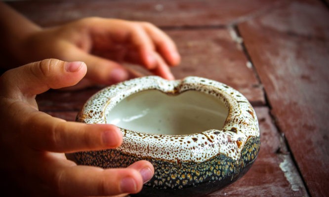 hands of a child trying to take empty ashtray